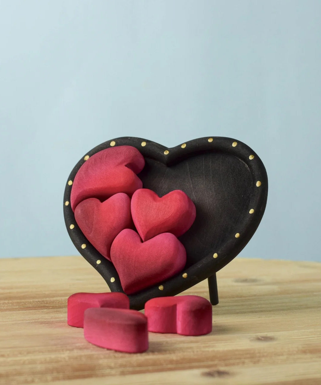 Bumbu wooden red hearts puzzle set in a wooden heart frame standing on a table with heart pieces on the table