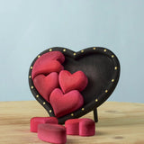 Bumbu wooden red hearts puzzle set in a wooden heart frame standing on a table with heart pieces on the table