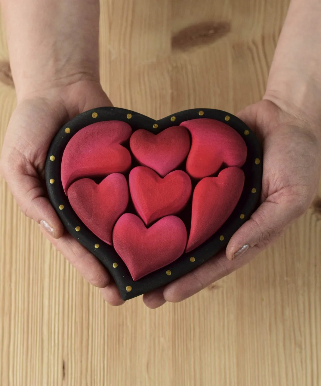 Bumbu wooden red hearts puzzle set in a wooden heart frame being held