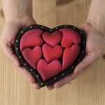 Bumbu wooden red hearts puzzle set in a wooden heart frame being held