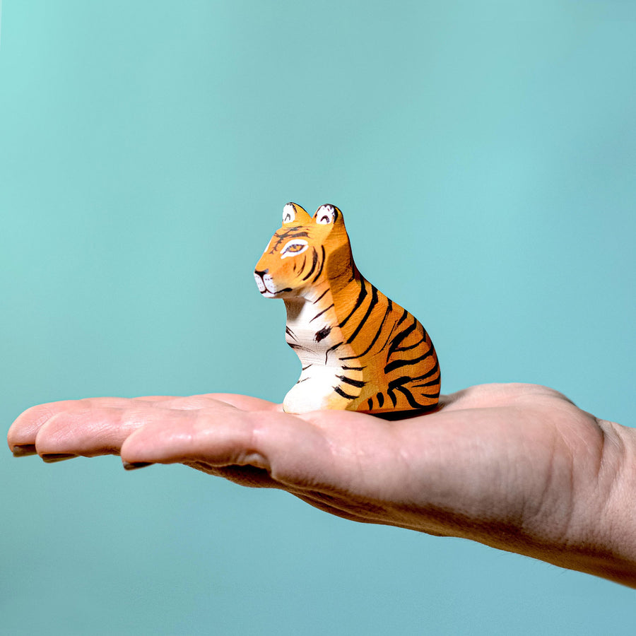 Person holding the Bumbu Wooden Sitting Tiger Cub in their hand