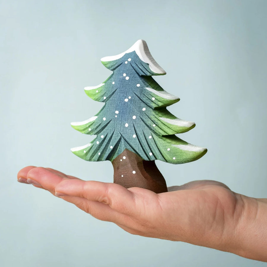 A Bumbu Small Snowy Fir Tree placed in the palm of an adult's hand. 