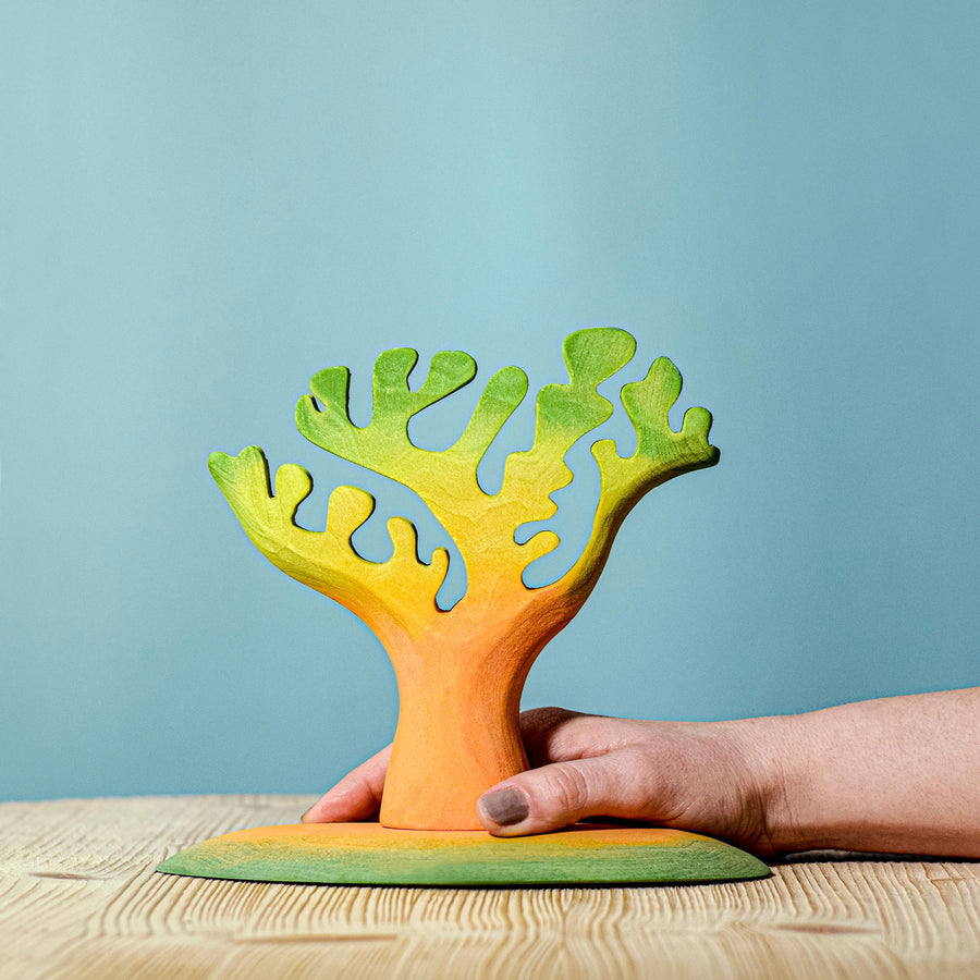 Bumbu Small Dino Tree pictured on a wooden surface with a blue background