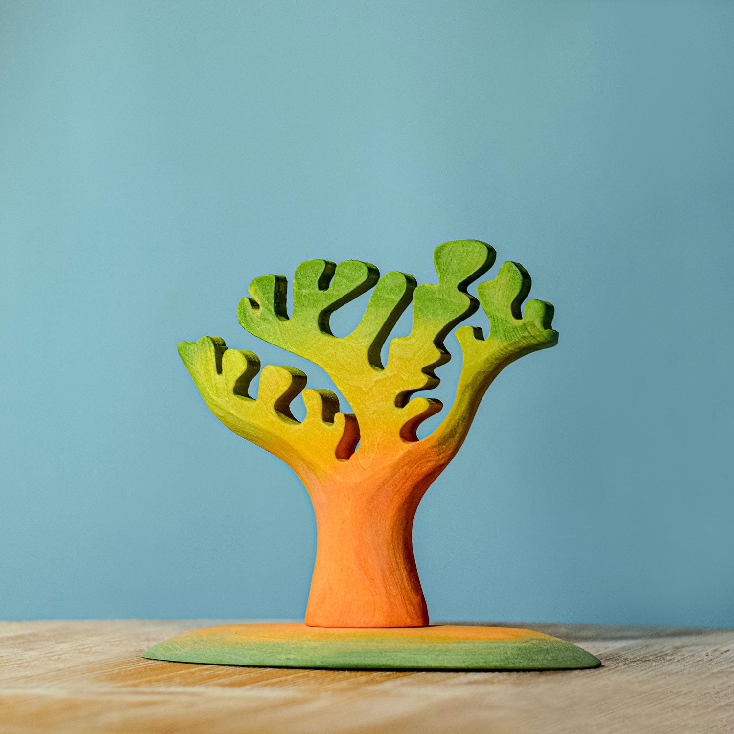 Bumbu small and big dino trees pictured placed on a wooden surface in front of a blue wall