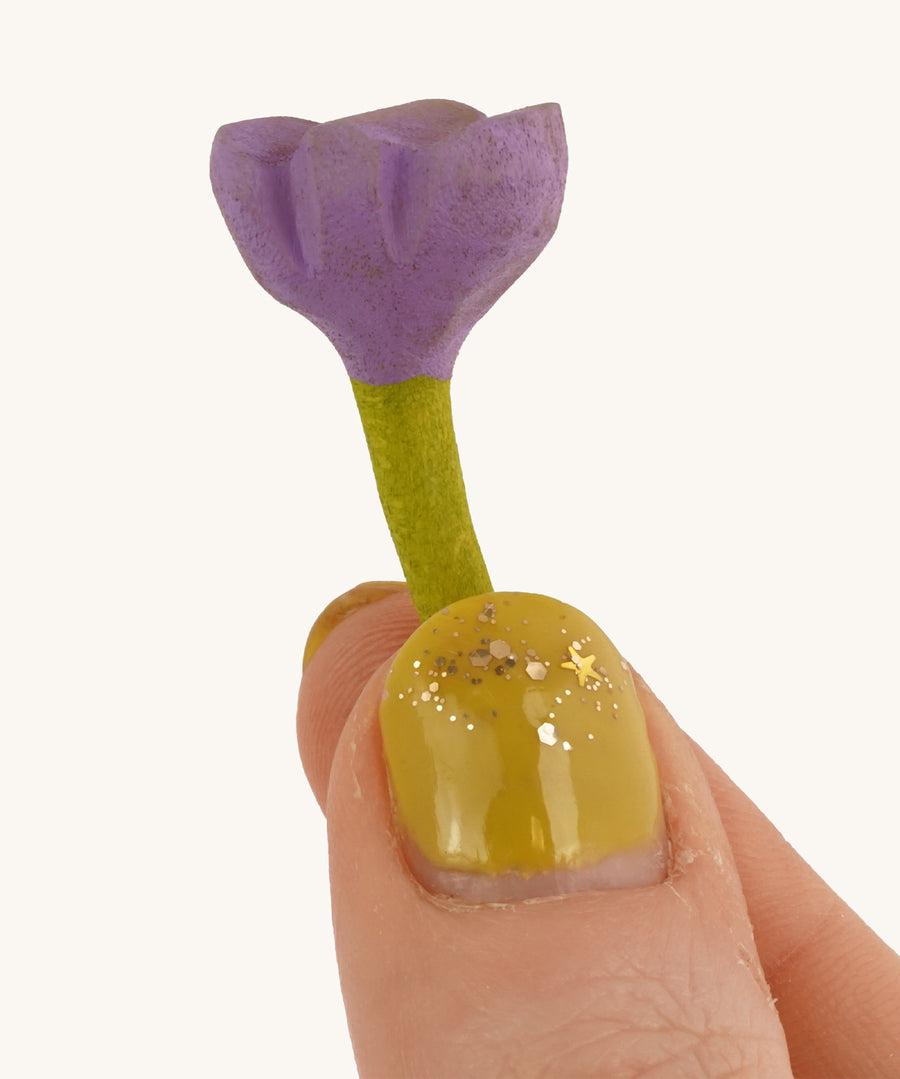 Bumbu Small Wooden Flower in lilac being held up in front of a cream background