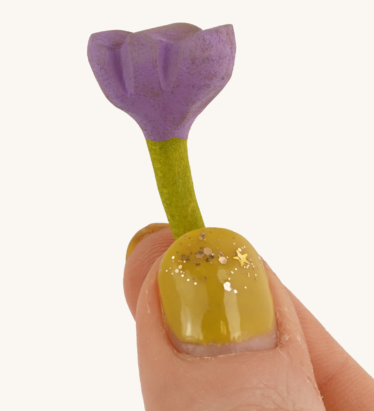 Bumbu Small Wooden Flower in lilac being held up in front of a cream background