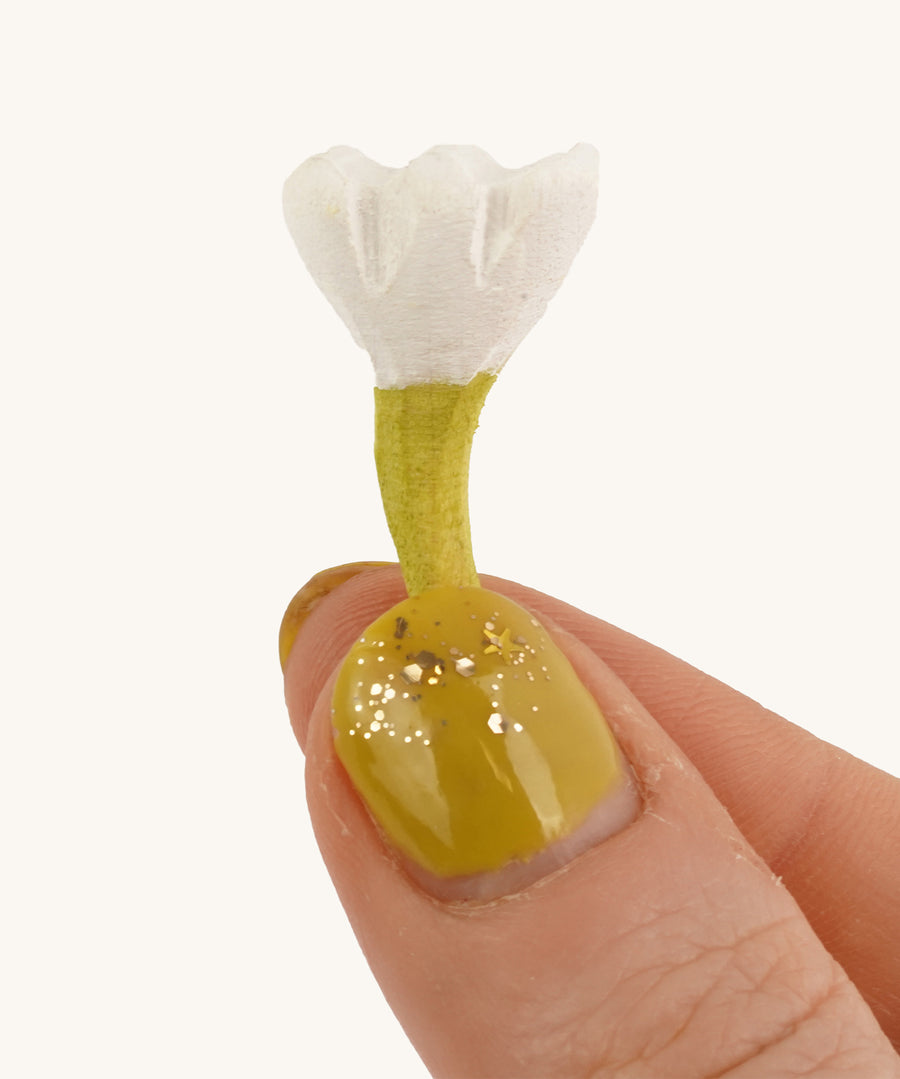 Bumbu Small Wooden Flower in white being held up in front of a cream background