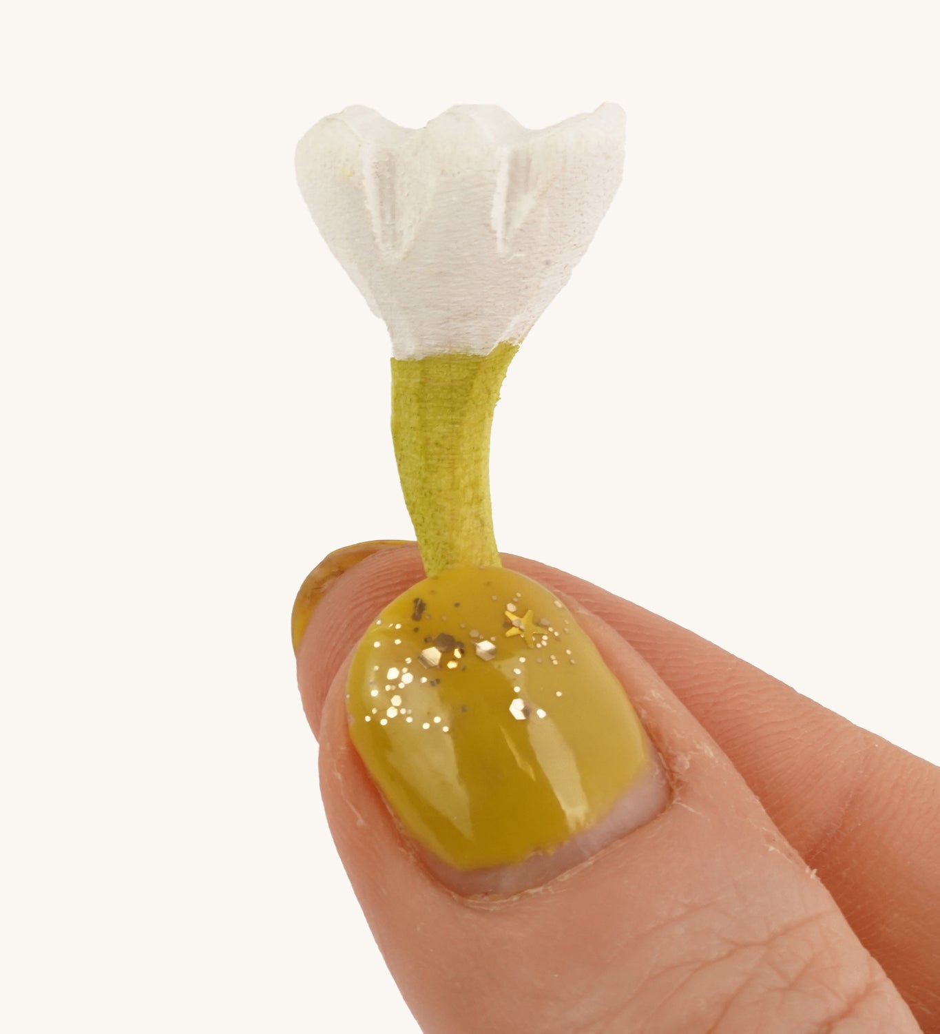 Bumbu Small Wooden Flower in white being held up in front of a cream background