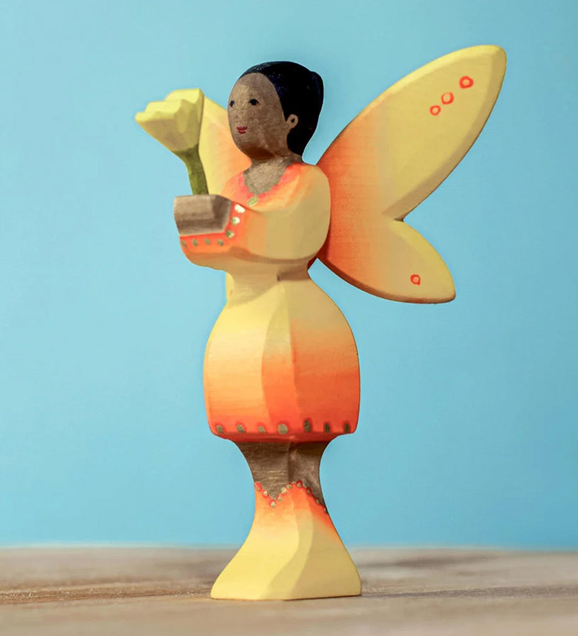 A Bumbu Small Wooden Flower in Yellow shown placed in the sunflower fairy's hands