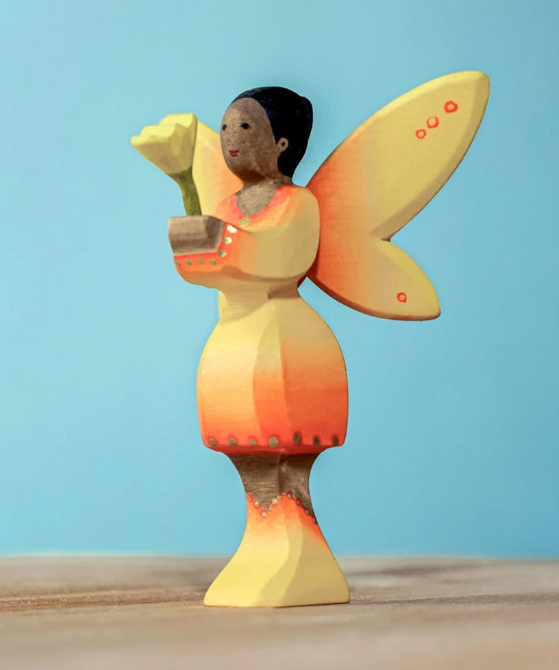 A Bumbu Small Wooden Flower in Yellow shown placed in the sunflower fairy's hands