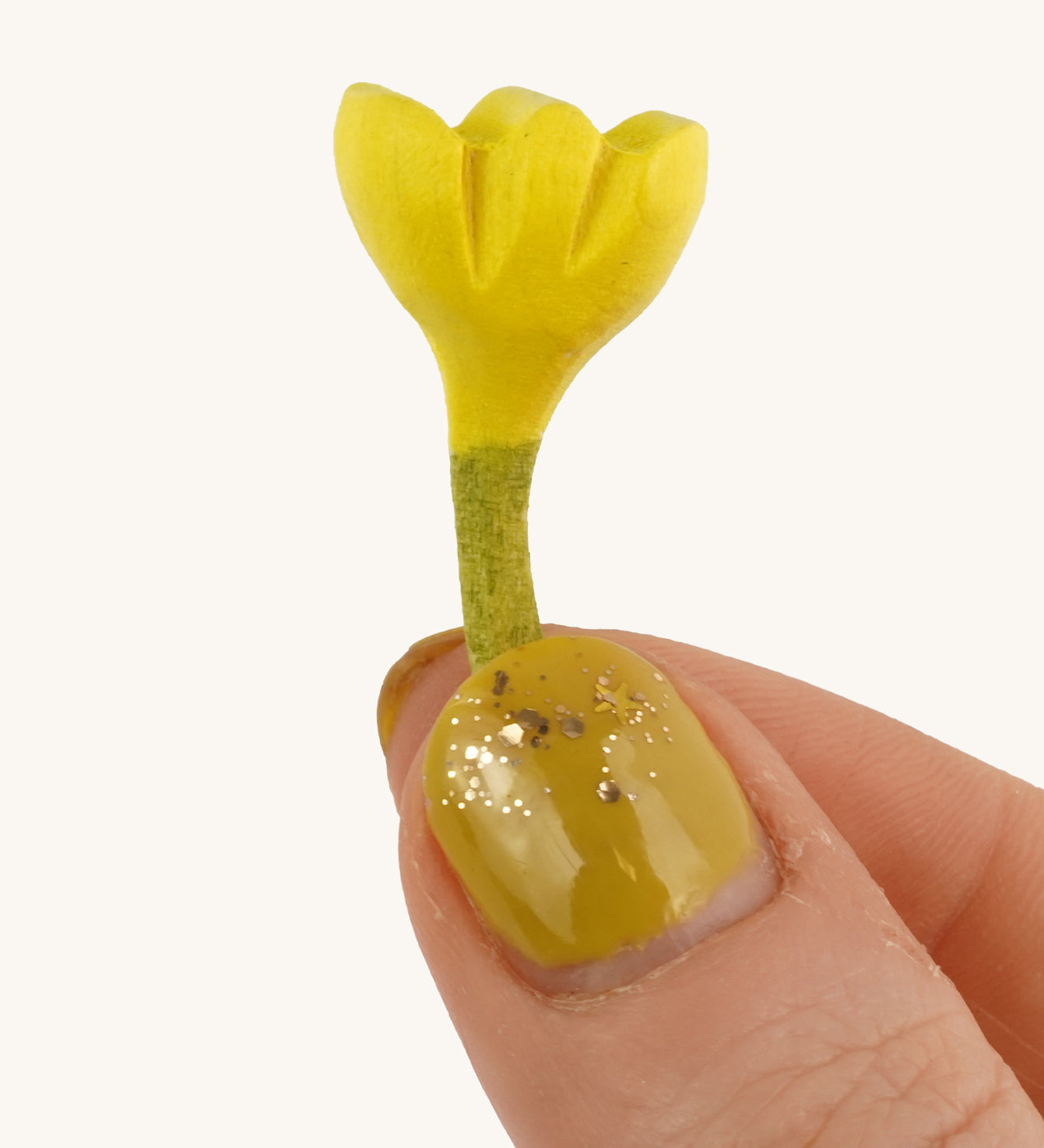 Bumbu Small Wooden Flower in Yellow bing held up in front of a cream background