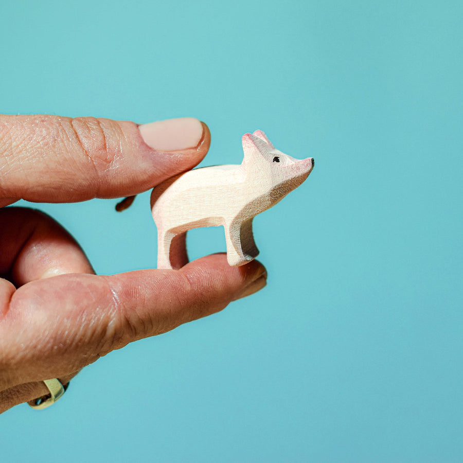 Person holding a Bumbu Wooden Standing Piglet between their finger and thumb