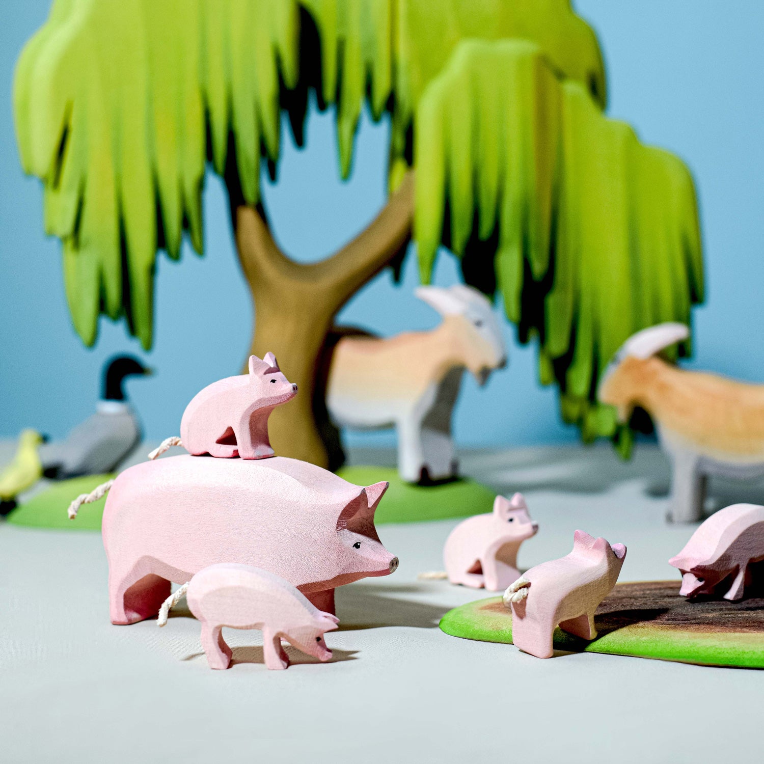 Bumbu wooden pig family  with other animals in background and a willow tree