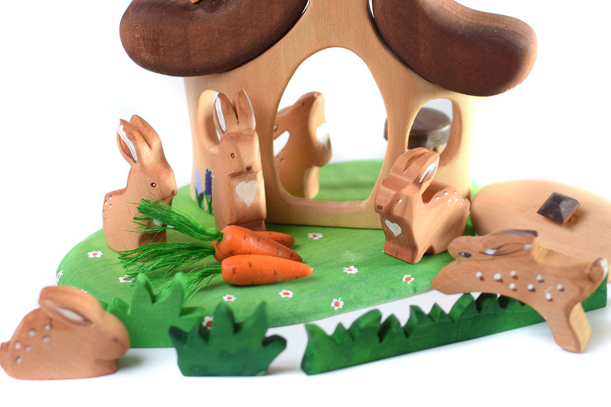 Close up of some Bumbu wooden rabbit toys inside the Bumbu hut in the forest play set on a white background