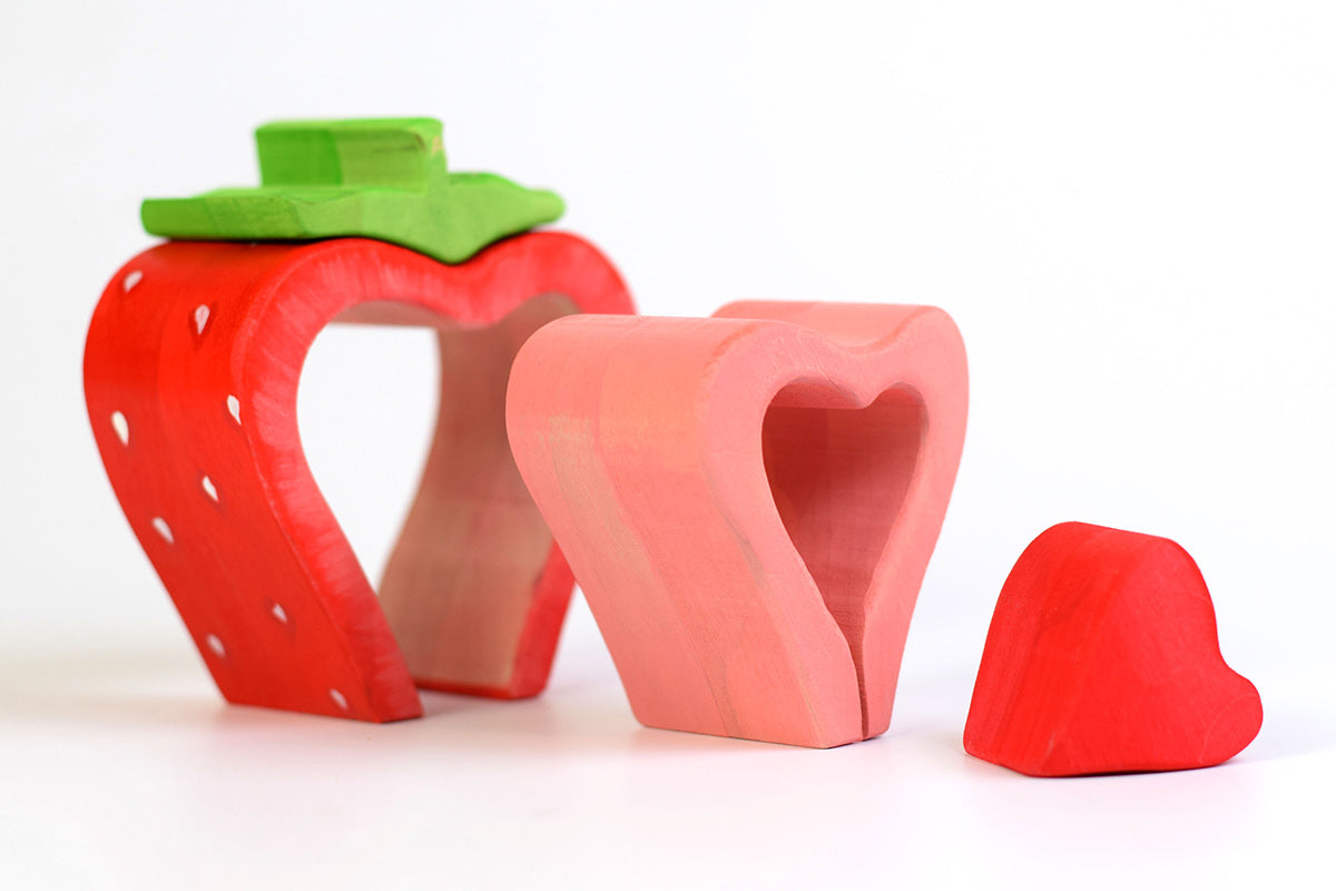 Pieces of the Bumbu eco-friendly wooden strawberry lined up on a white background