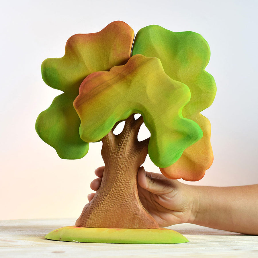 Hand holding the eco-friendly Bumbu autumn oak tree on a wooden background