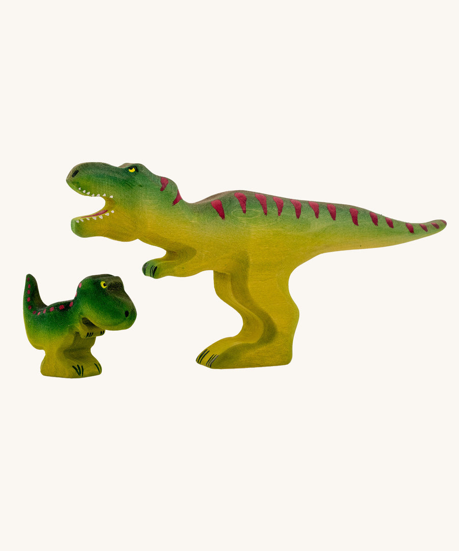 Bumbu Baby and large Wooden T-Rex Dinosaurs on a plain background.