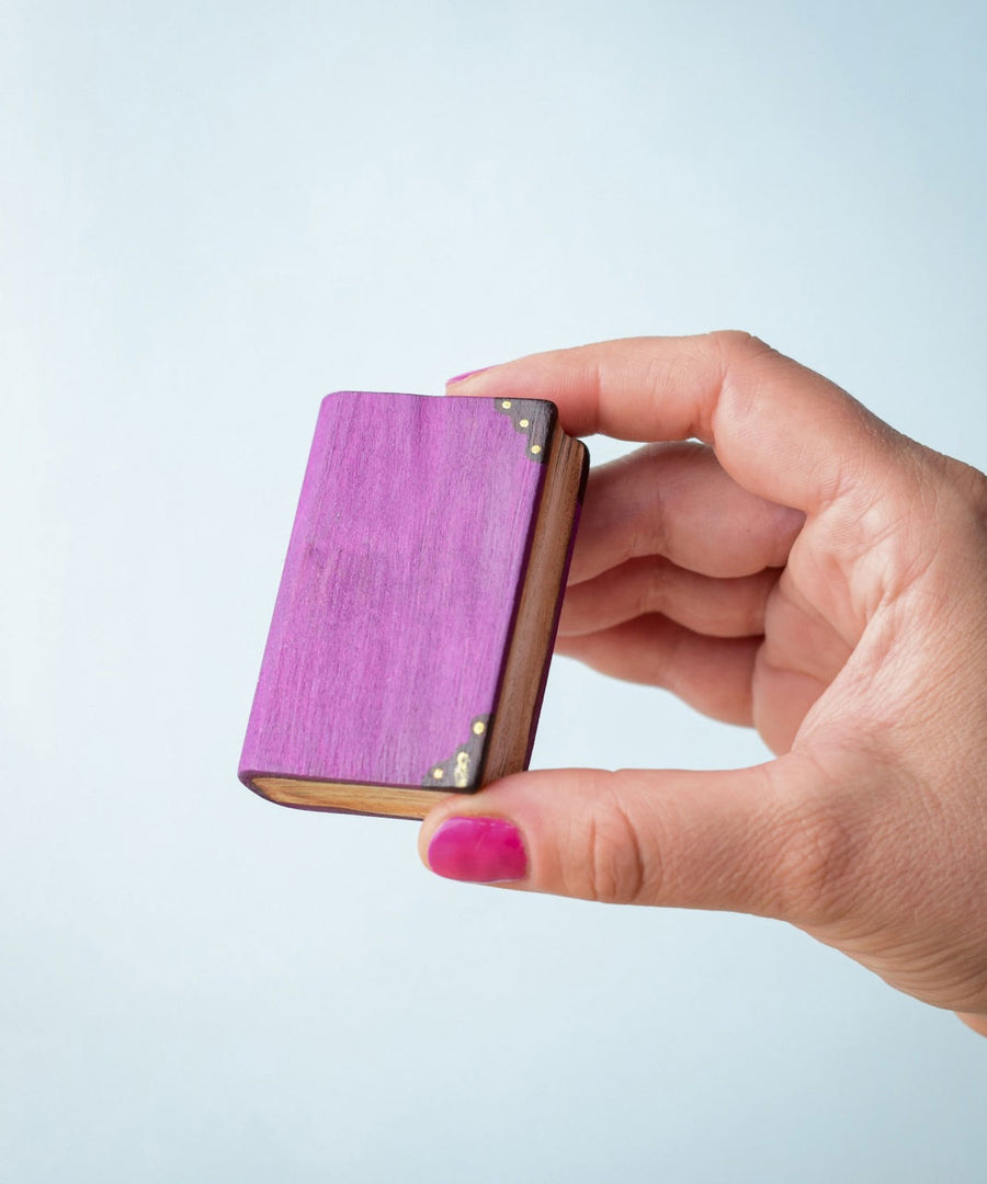 Bumbu Toys Large purple Book being held in an adult's hand. The person has pink painted fingernails.