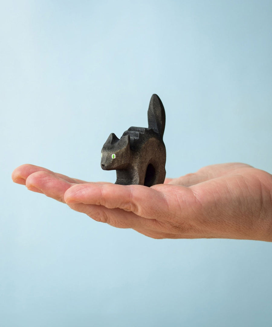 Bumbu Toys Scared Black Cat figure. The cat's tail is stood up and the cat has green eyes. The cat is balanced on a palm of an adult's hand. 