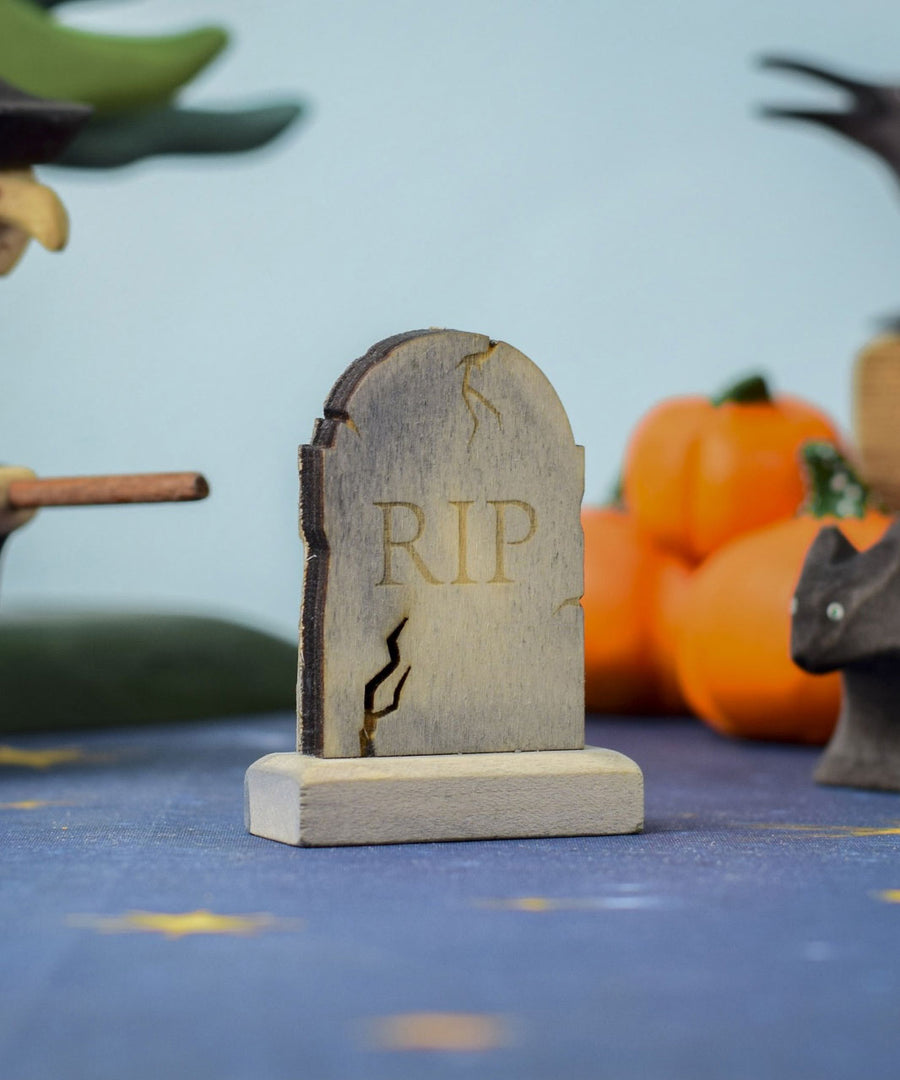 The RIP decorated headstone from the Bumbu Toys Gravestones Set, the gravestone has crack detailing on the edges giving it a spooky Halloween vibe. The headstone is pictured in a Halloween themed play scene. 