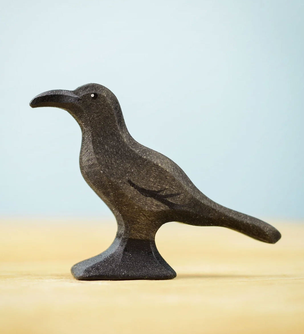 Bumbu Toys Raven wooden figure. The figure is on a wooden surface. 