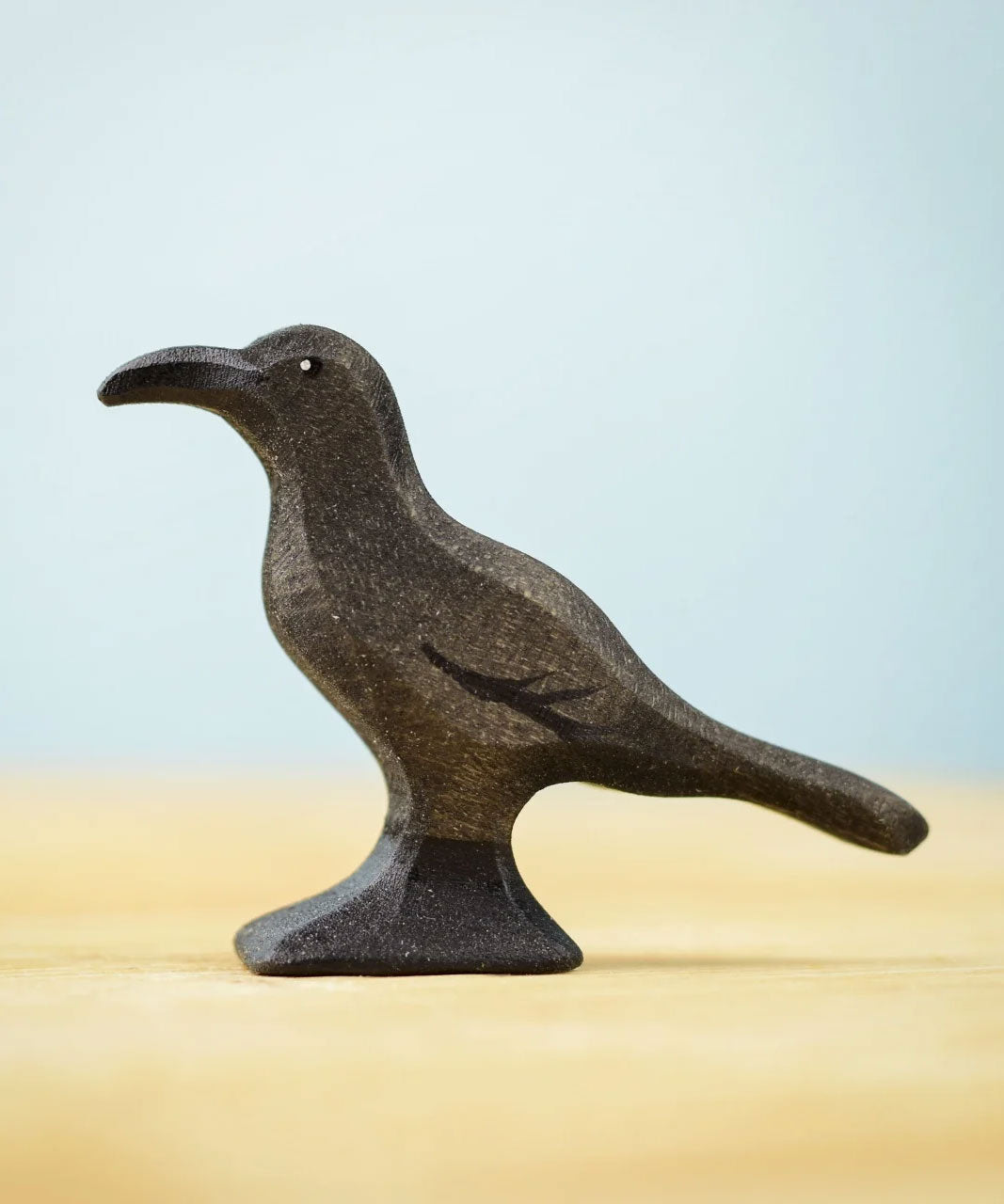 Bumbu Toys Raven wooden figure. The figure is on a wooden surface. 