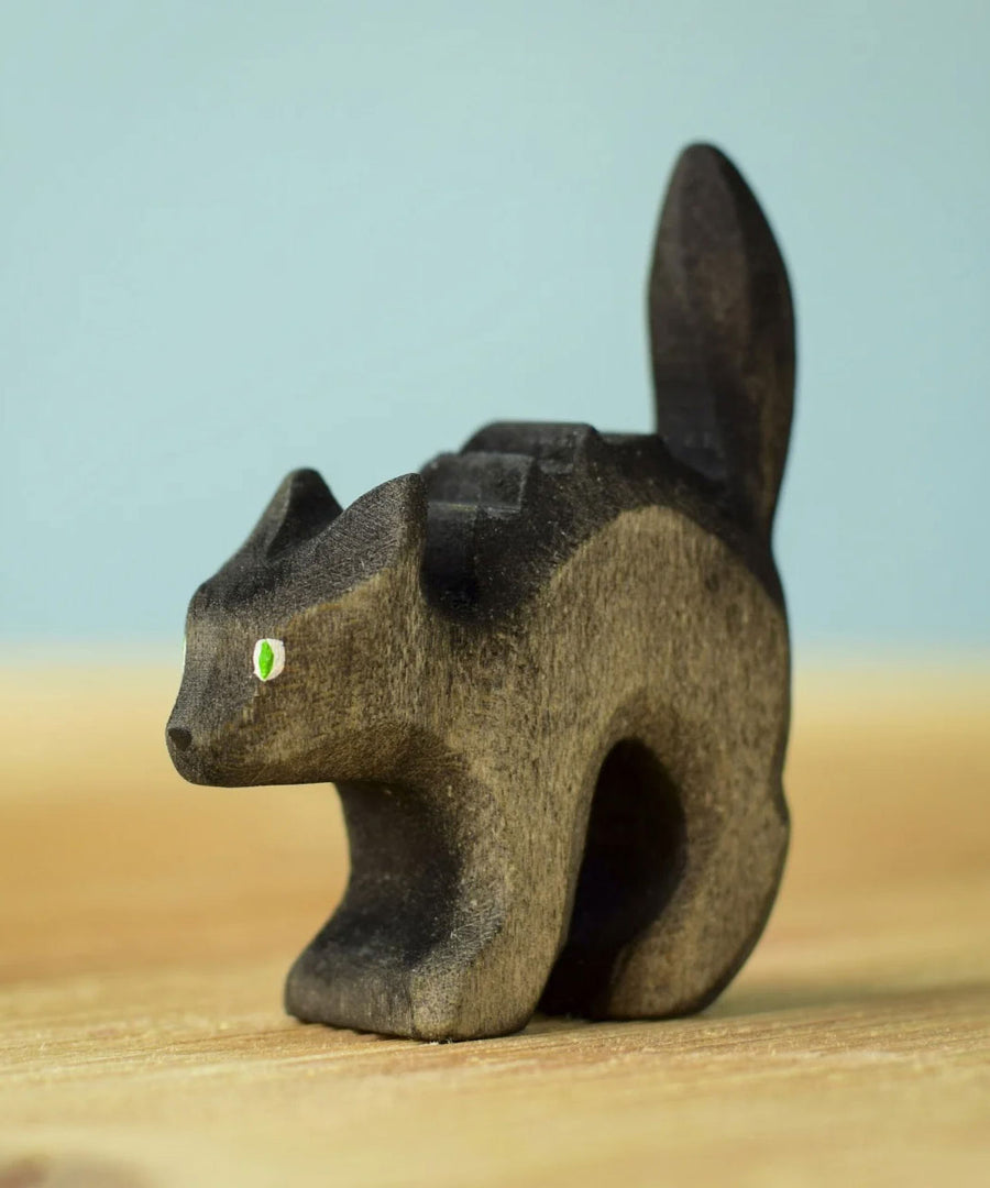 Bumbu Toys Scared Black Cat figure. The cat's tail is stood up and the cat has green eyes. The cat is placed on a wooden surface.