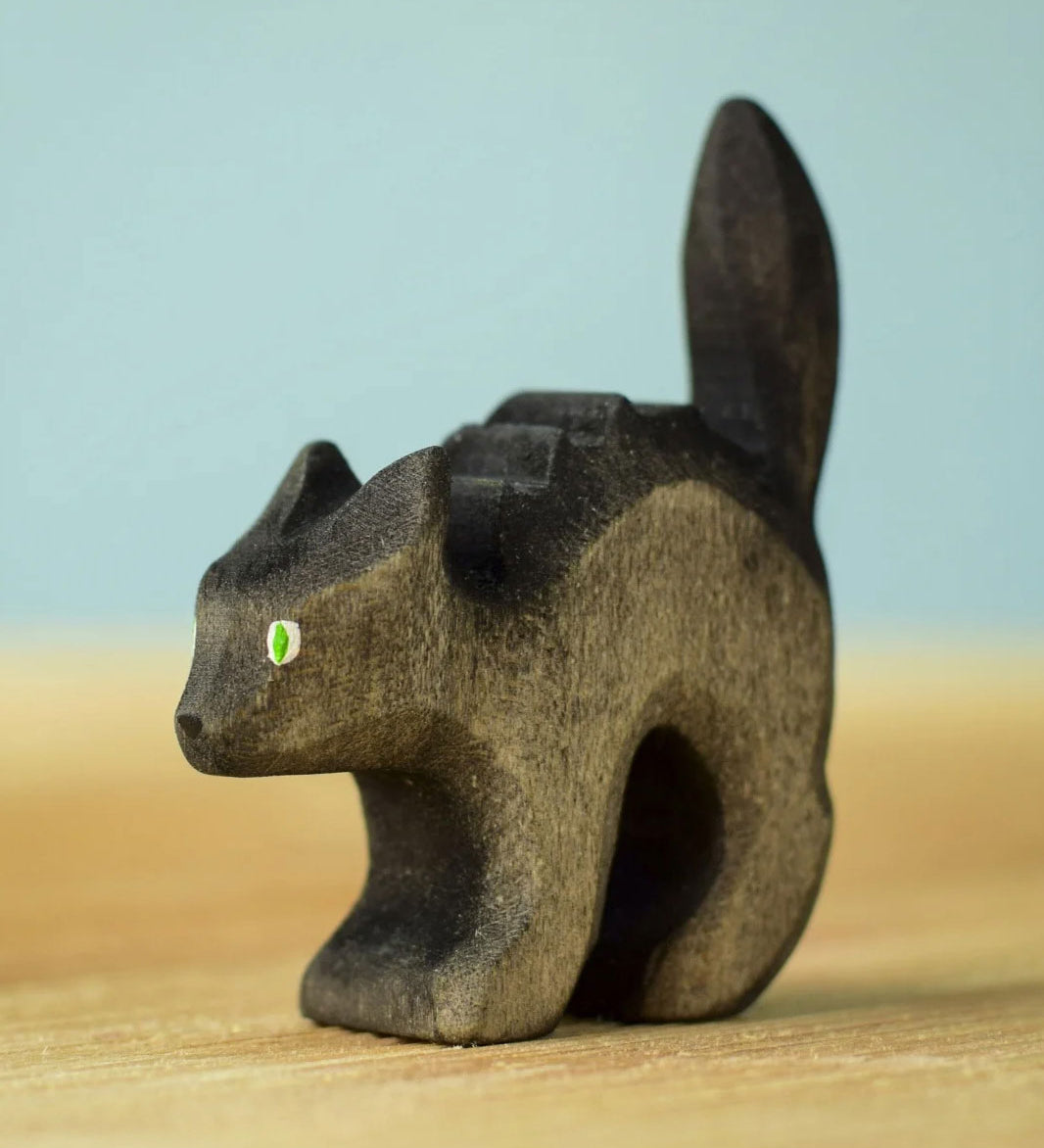 Bumbu Toys Scared Black Cat figure. The cat's tail is stood up and the cat has green eyes. The cat is placed on a wooden surface.