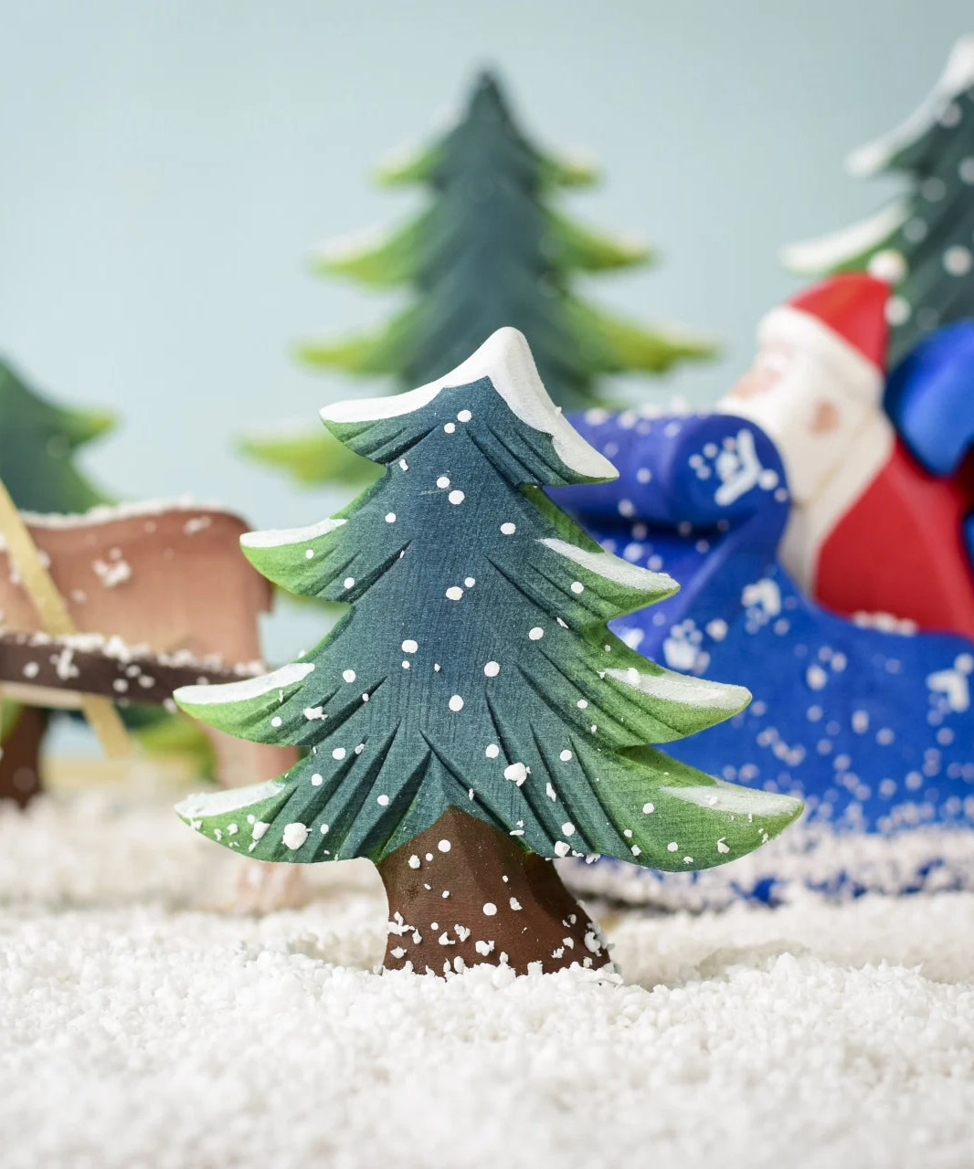 A Bumbu Small Snowy Fir Tree placed in the centre of a festive small world play scene. 