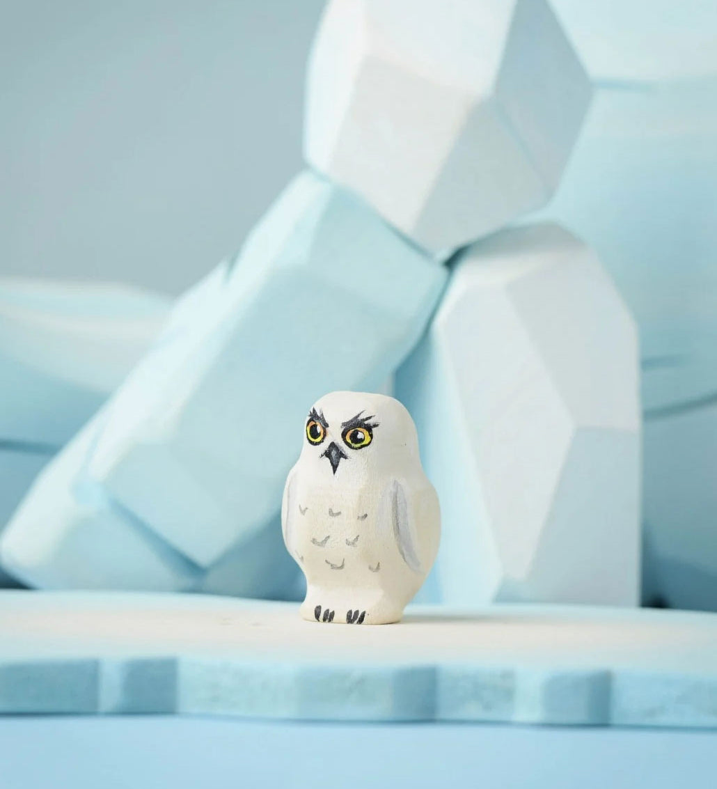 The Bumbu Toys Snowy Owl Chick placed on a Bumbu ice floe with the Bumbu icy rocks in the background. 