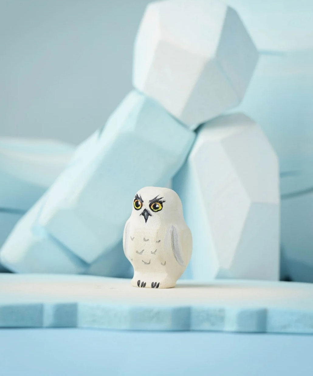 The Bumbu Toys Snowy Owl Chick placed on a Bumbu ice floe with the Bumbu icy rocks in the background. 