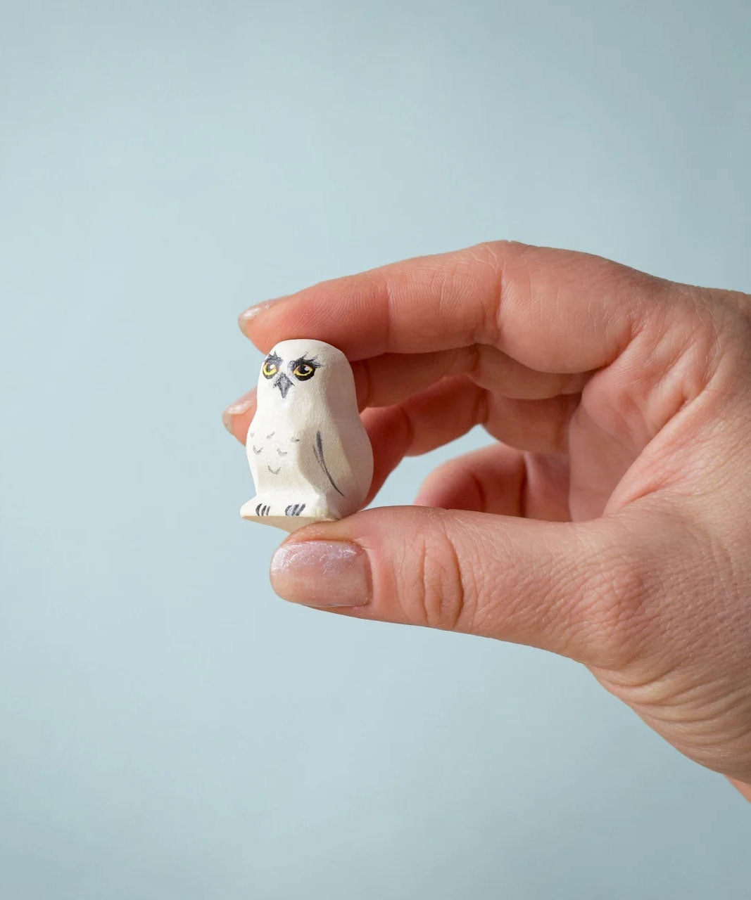 An close up of the Bumbu Toys Snowy Owl Chick being held in an adult's hand. 