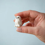 An close up of the Bumbu Toys Snowy Owl Chick being held in an adult's hand. 