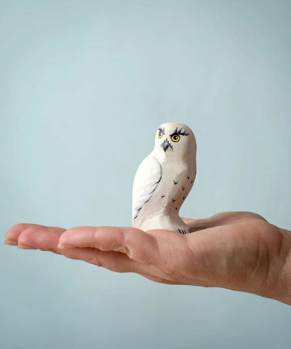 The Bumbu Toys Snowy Owl on the palm of an adult's hand. 