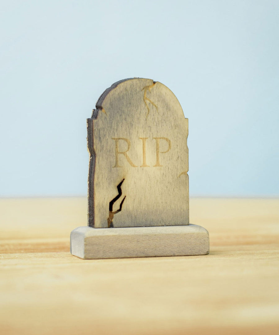 The RIP decorated headstone from the Bumbu Toys Gravestones Set. The headstone is placed on a wooden surface.