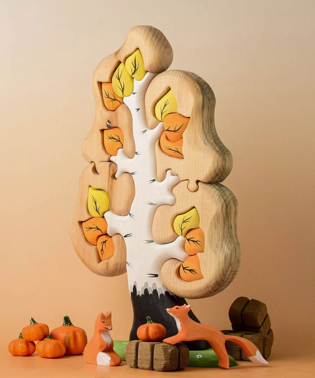 A small world play set up featuring the Bumbu Toys Big Puzzle Birch Tree with Bumbu pumpkins, wooden bales and foxes.