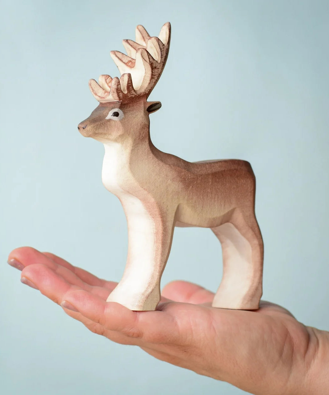 A Bumbu Toys Reindeer placed in the palm of an adult's hand.