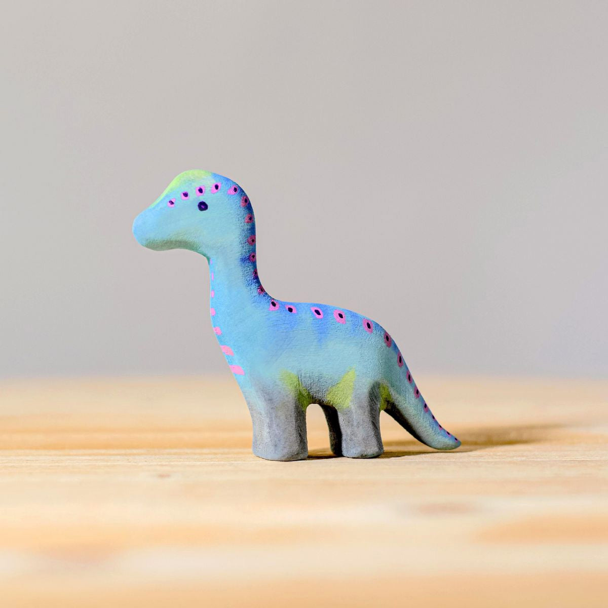 A child playing with the Bumbu Brontosaurus toys and natural dino toys on a window sill