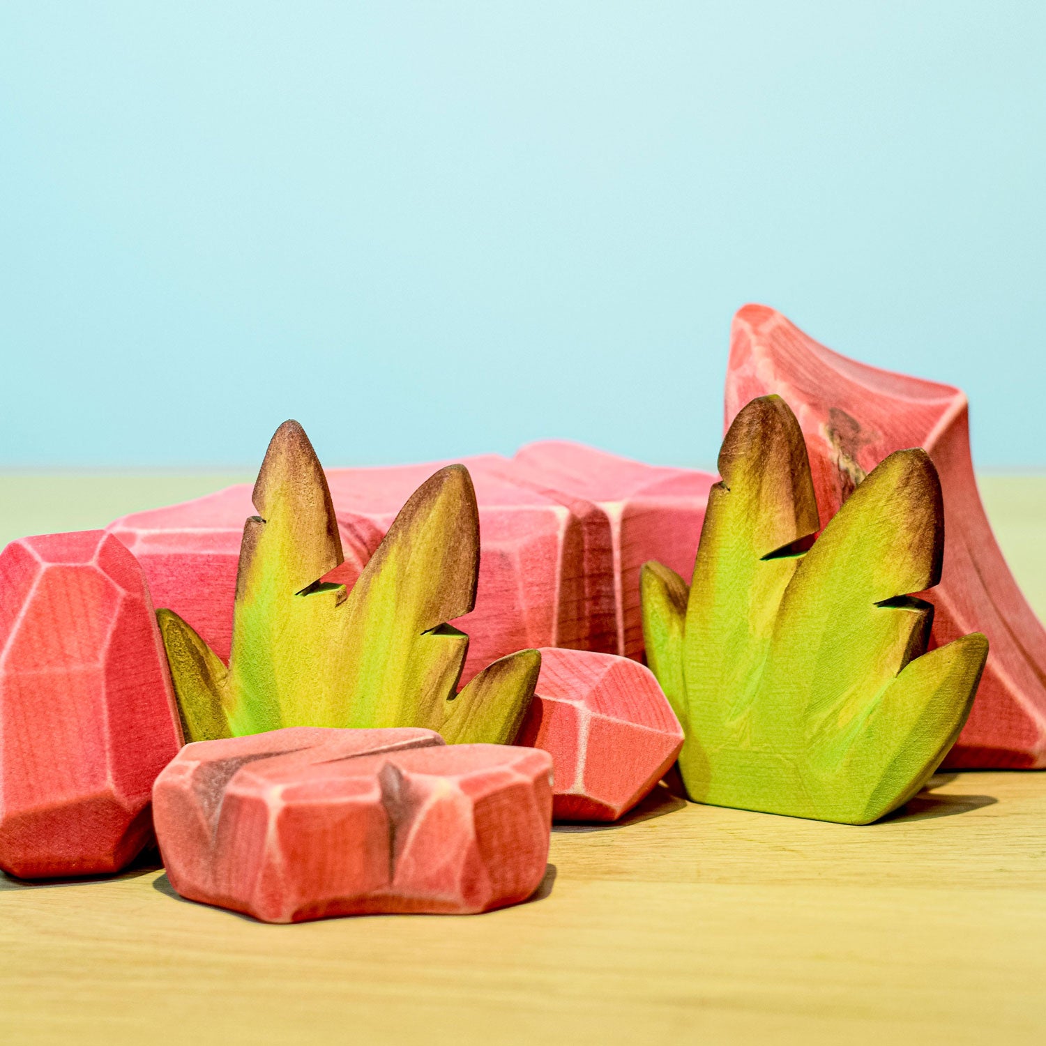 Bumbu Wooden Banana Bush pictured in an adults hand in front of a blue wall