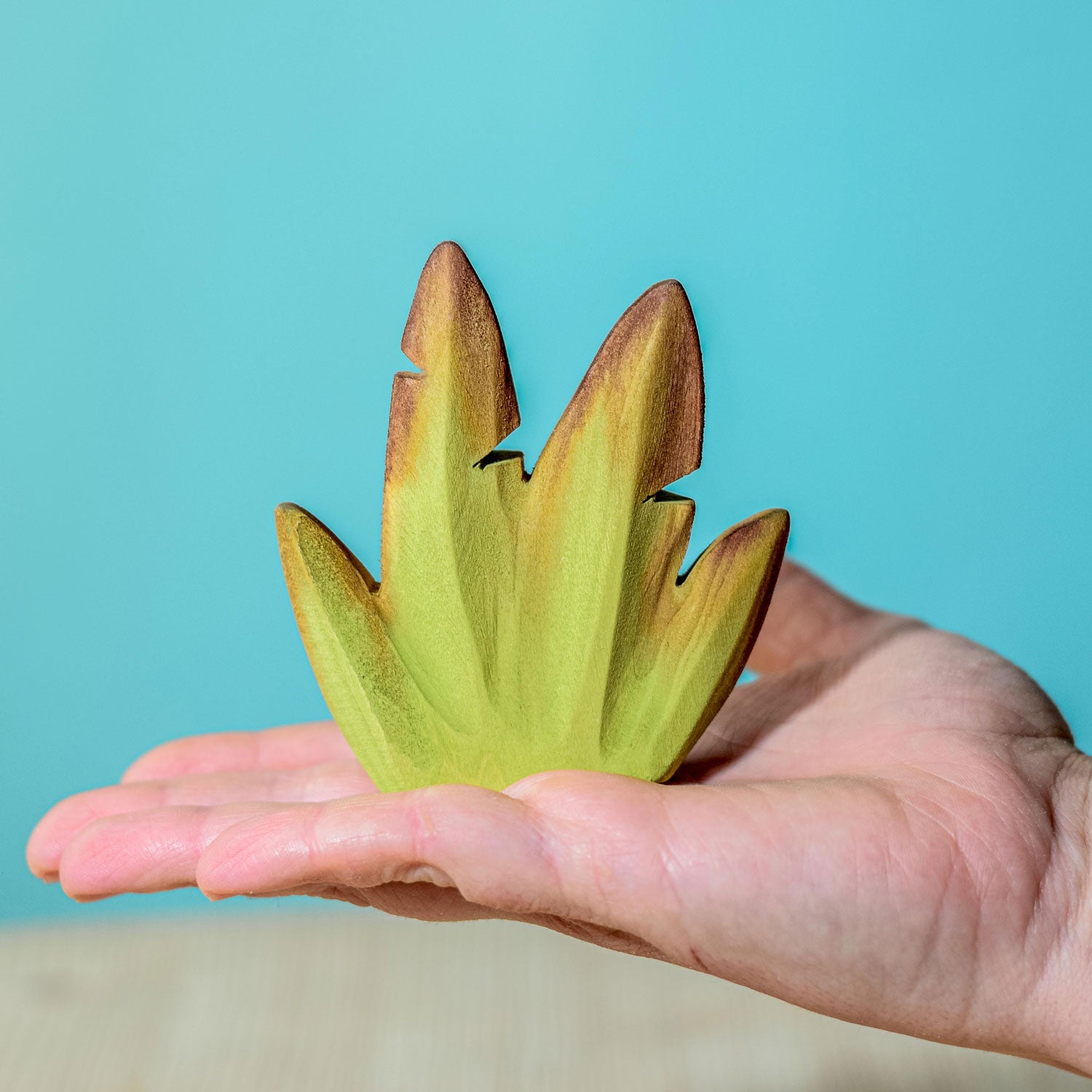 Bumbu Wooden Banana Bush placed on a wooden surface in front of a blue wall