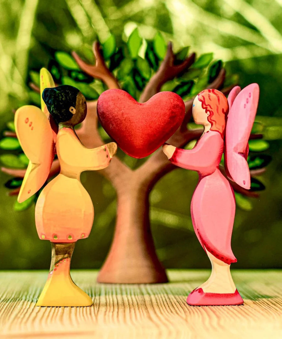 A Bumbu sunflower fairy and a blossom fairy holding up the heart from the heart tree. The rest of the heart tree can be seen in the background.