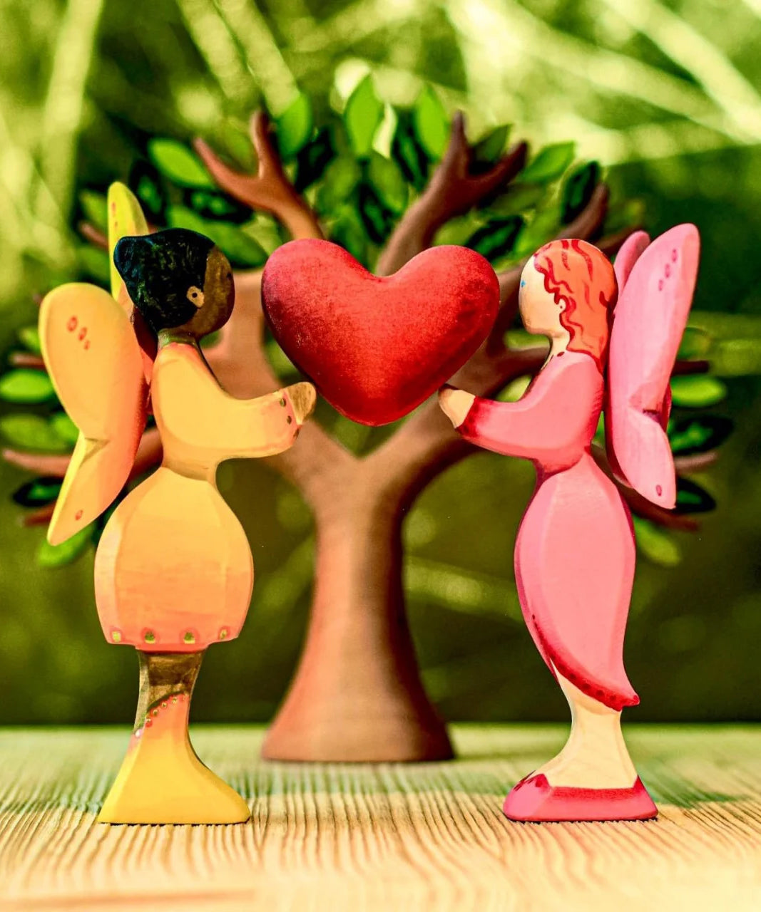 A Bumbu sunflower fairy and a blossom fairy holding up the heart from the heart tree. The rest of the heart tree can be seen in the background.