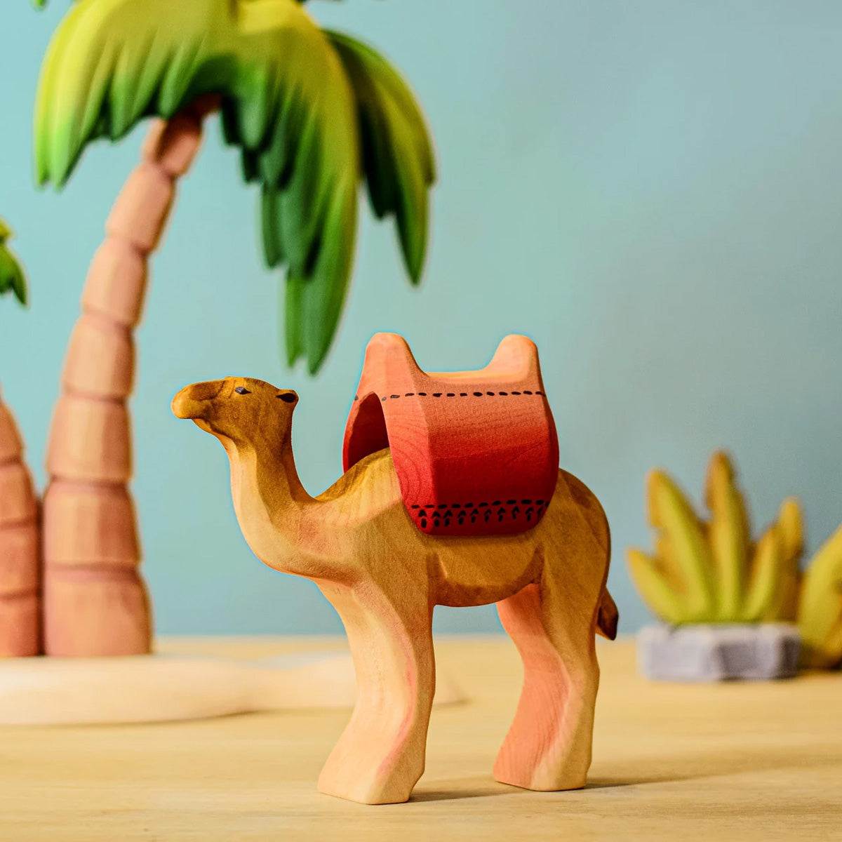 Bumbu handmade wooden camel figure wearing a red saddle