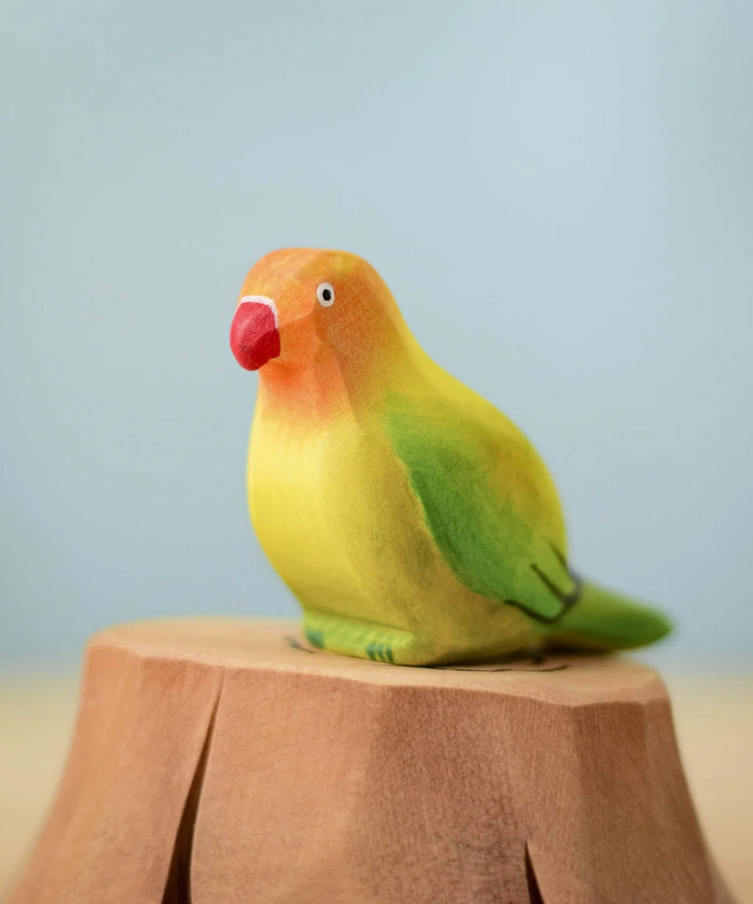 Bumbu wooden green lovebird figure perched on a Bumbu wooden stump