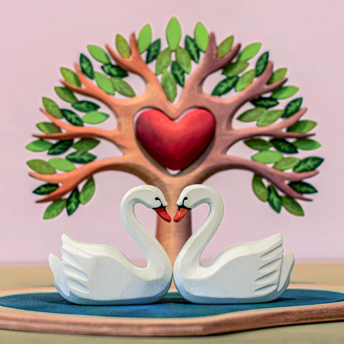 Two Bumbu Miniature Wooden peckers sit in the Bumbu Wooden Heart Tree. One is one top of the tree and the other is sitting in the heart cut out