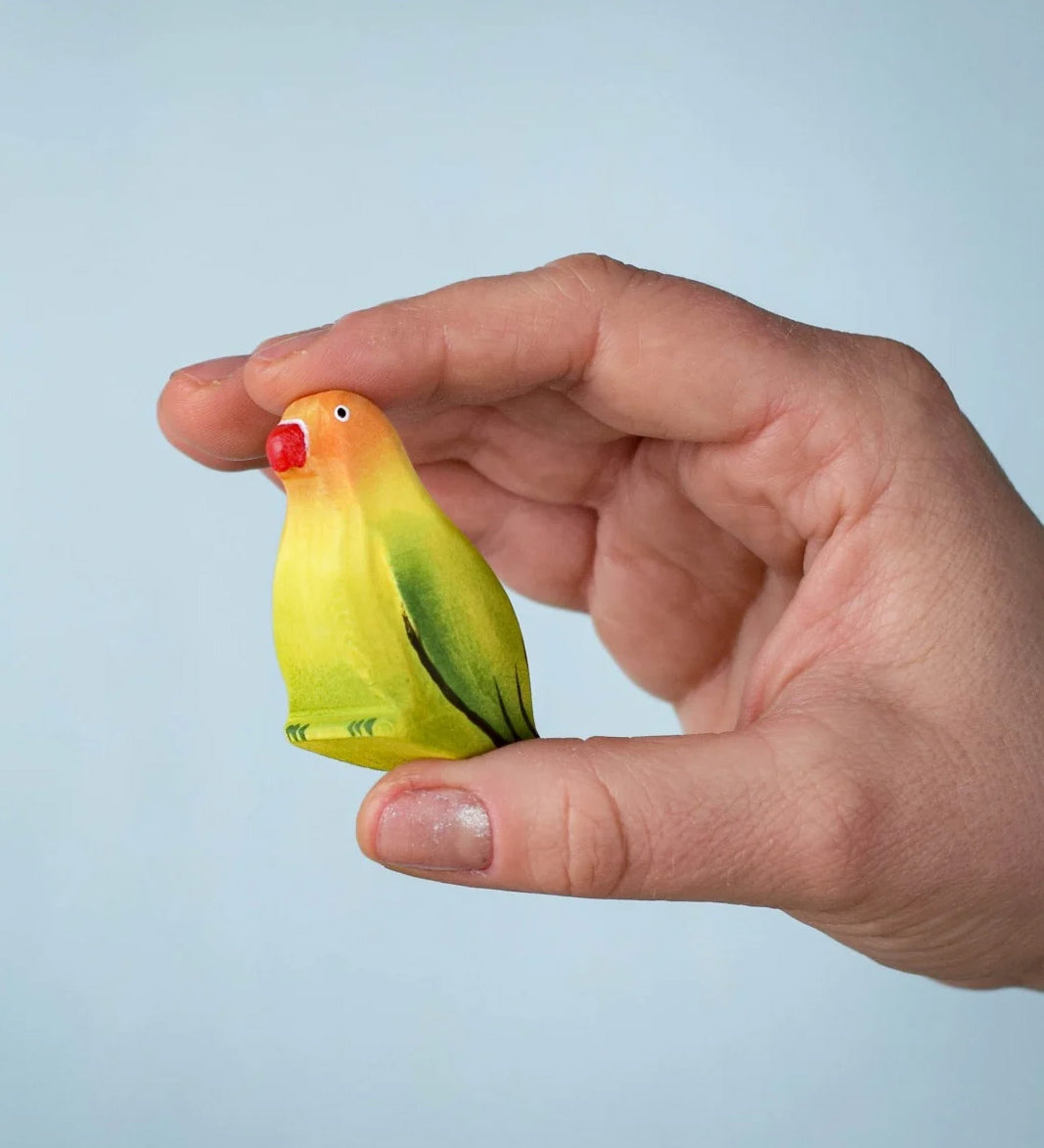 Bumbu wooden blue lovebird figure held by an adult hand