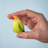 Bumbu wooden blue lovebird figure held by an adult hand