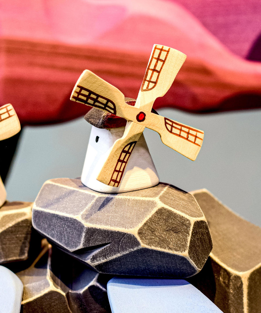 Bumbu Miniature Wooden Moldova Windmill. The toy sits on a wooden surface against a blue background. The blades and mill sit separately.