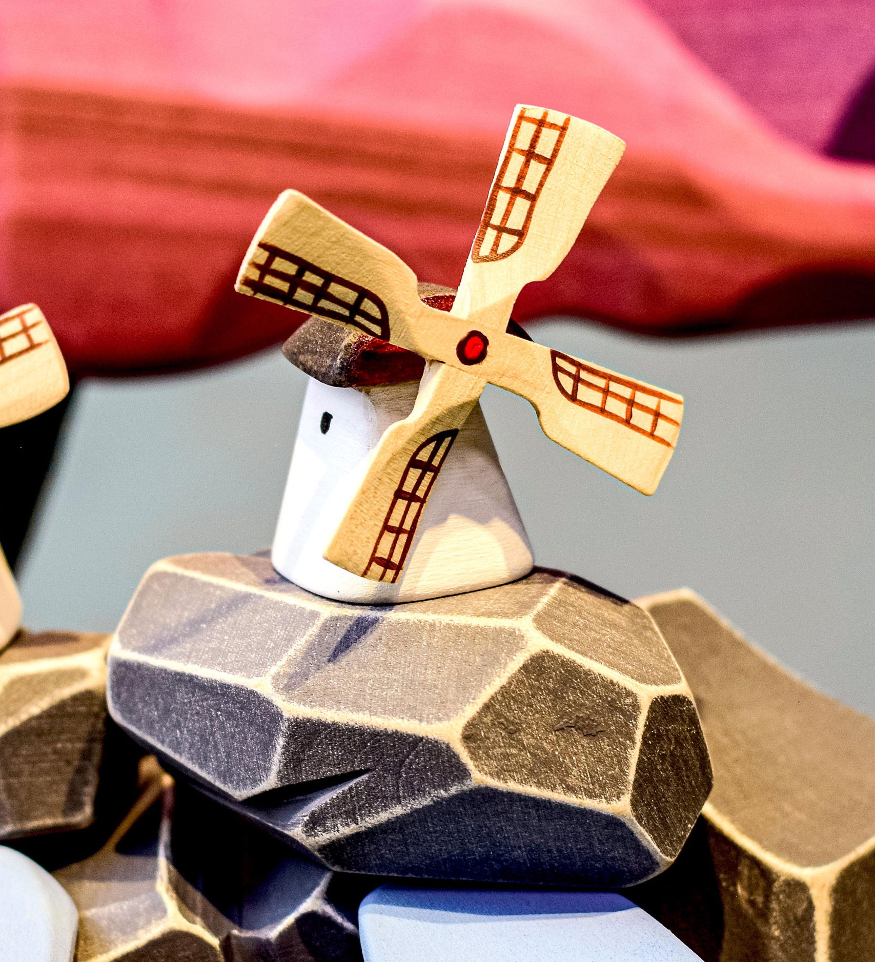 Bumbu Miniature Wooden Moldova Windmill. The toy sits on a wooden surface against a blue background. The blades and mill sit separately.