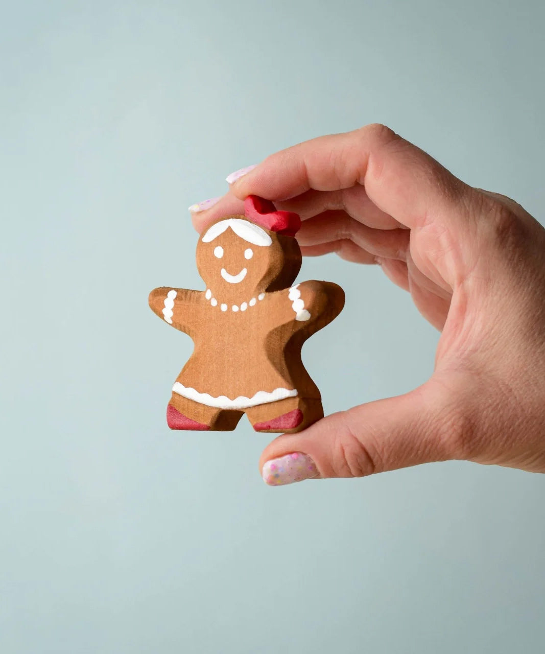 A hand holding the Bumbu wooden gingerbread cookie girl